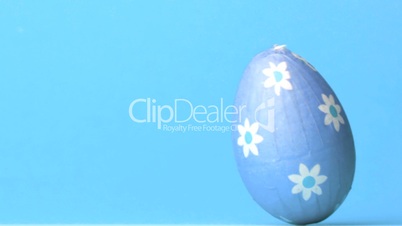 Blue easter egg rolling across blue background