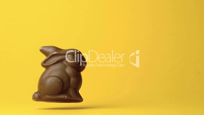 Chocolate bunny falling against yellow background