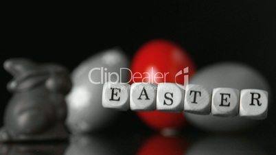 Dice spelling out easter falling in front of easter treats and egg black and white