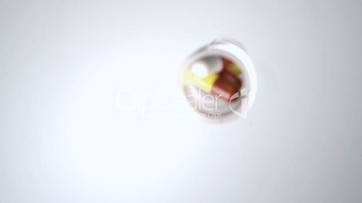 Jar of pills falling onto white surface