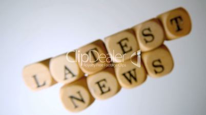 Latest news spelled out in dice falling on white surface