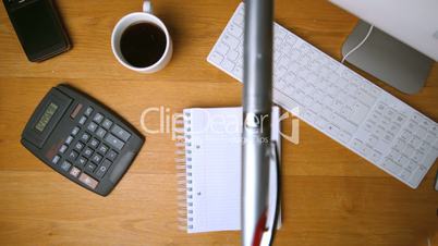 Fountain pen falling onto notepad on office desk