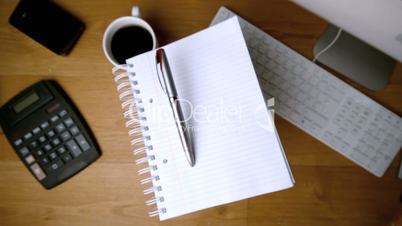 Fountain pen and notepad falling onto office desk