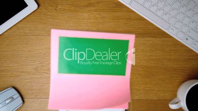 Pink sticky notes with chroma key falling onto office desk