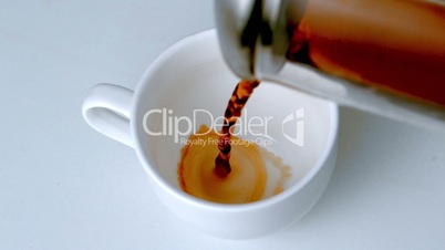 Coffee pouring from cafetiere into white cup