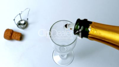 Champagne being poured into flute on white surface high angle view