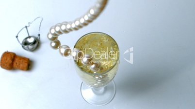 String of pearls dropping in glass of champagne