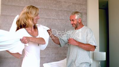 Mature couple having a pillow fight and laughing