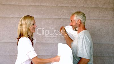 Mature couple pillow fighting at home