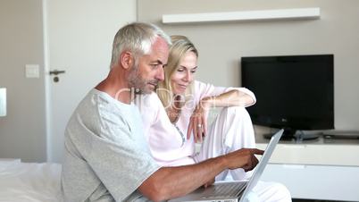 Couple using laptop together in the bedroom