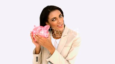 Businesswoman shaking piggy bank