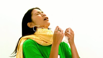 Asian woman in green tshirt and yellow scarf sneezing