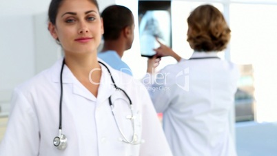 Doctor standing and smiling in front of medical team