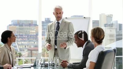 Businessman presenting to his team who applaud him