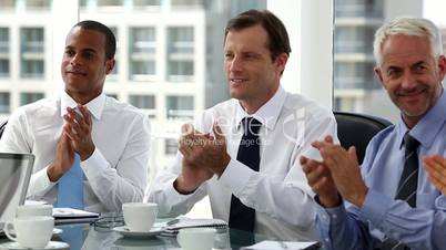 Business people clapping sitting in board room