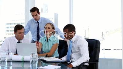 Businesswoman explaining something to her colleagues while using a laptop