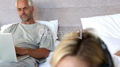 Calm woman listening to music next to her husband 