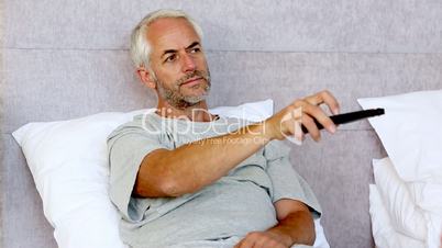 Man sitting in his bed while watching television