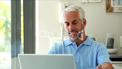 Serious man using his laptop while drinking a coffee 