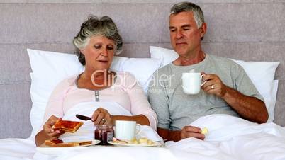 Mature couple enjoying breakfast in bed