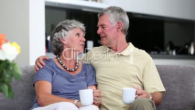Mature couple chatting together with a cup of coffee on a sofa