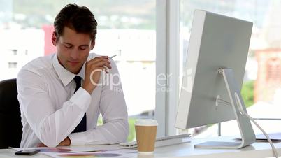 Businessman examining documents helped by his computer