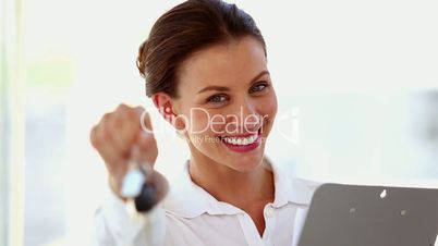 Smiling businesswoman shaking keys in front of the camera
