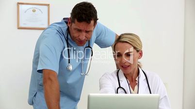 Two doctors using a laptop together in their office