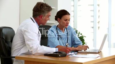 Doctors talking together in front of a laptop