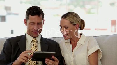 Colleagues laughing together while working on a tablet