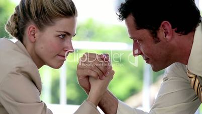 Businesswoman and businessman arm wrestling