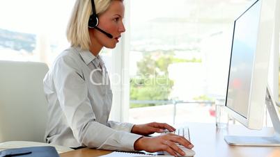 Businesswoman talking on headset and typing
