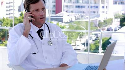 Doctor working on the phone and laptop