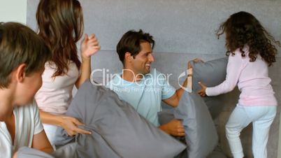 Smiling family having a pillow fight