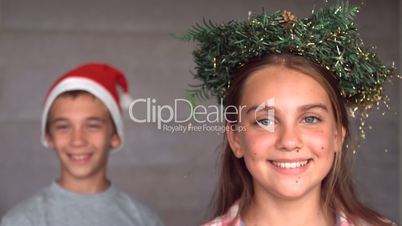 Siblings wearing garland and hat to celebrate christmas