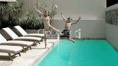 Brother and sister diving into the swimming pool