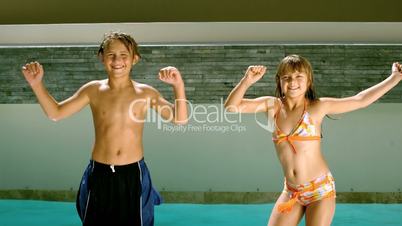 Siblings dancing together in front of the swimming pool