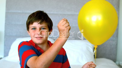 Boy piercing his balloon in the bedroom