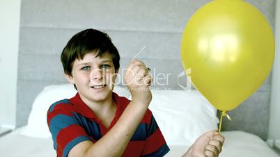 Boy piercing his yellow balloon and getting a fright