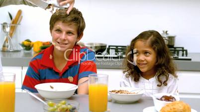 Dad pouring cereal into his children bowls during breakfast