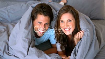 Couple having fun wrapped in their duvet