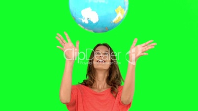 Woman throwing a globe in the air on green screen