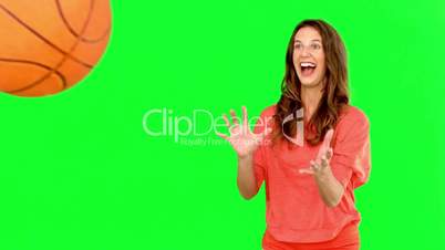 Smiling woman catching a basket ball on green screen