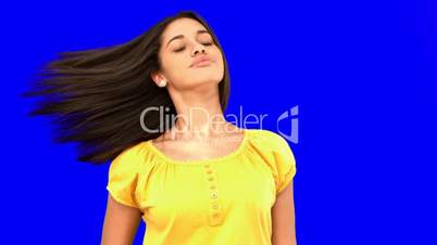 Smiling woman tossing her hair on blue screen