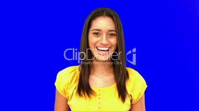 Confused woman being surprised then laughing on blue screen