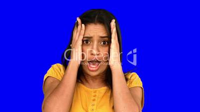 Shocked woman putting hands on head on blue screen