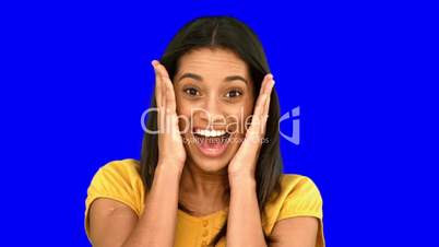 Surprised woman holding her head on blue screen