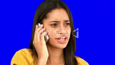 Upset woman talking on the phone on blue screen
