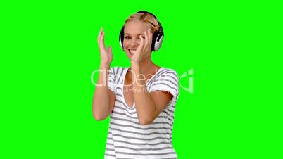 Young woman listening to music on green screen