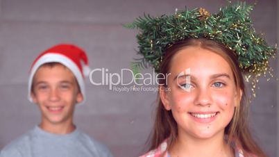 Siblings wearing garland and hat to celebrate christmas